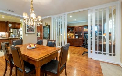 Une salle à manger chaleureuse avec une table en bois, des chaises en cuir et un lustre, reliée à un espace bureau.