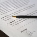 Document avec stylo et signature manuscrite, texte flou en arrière-plan