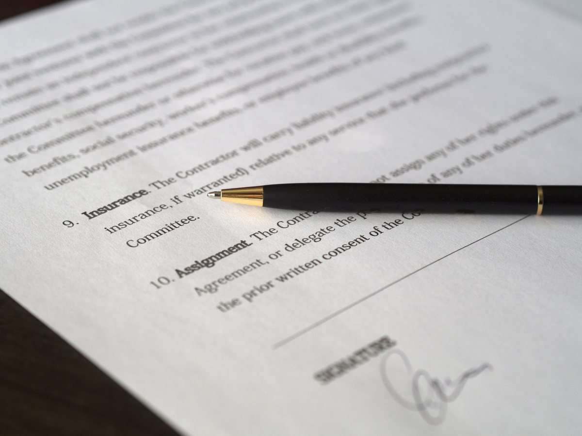 Document avec stylo et signature manuscrite, texte flou en arrière-plan
